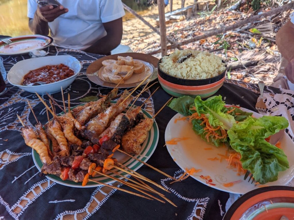 A plate of grilled prawn and fish skewers served with rice and salad at a Madagascar beach restaurant
