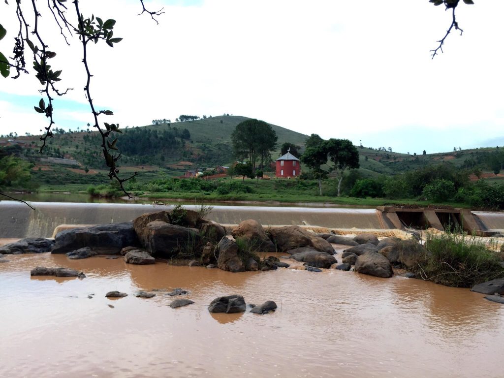 A highland village of tiled brick houses perched above a weir on a muddy river