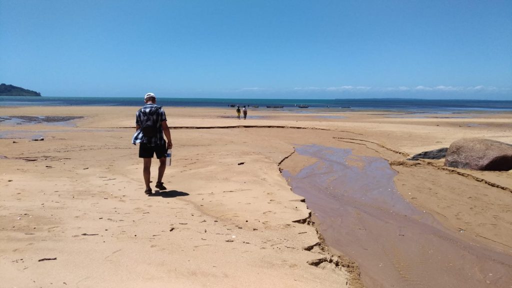 A solitary figure crossing a vast empty sandflat exposed by the low tide