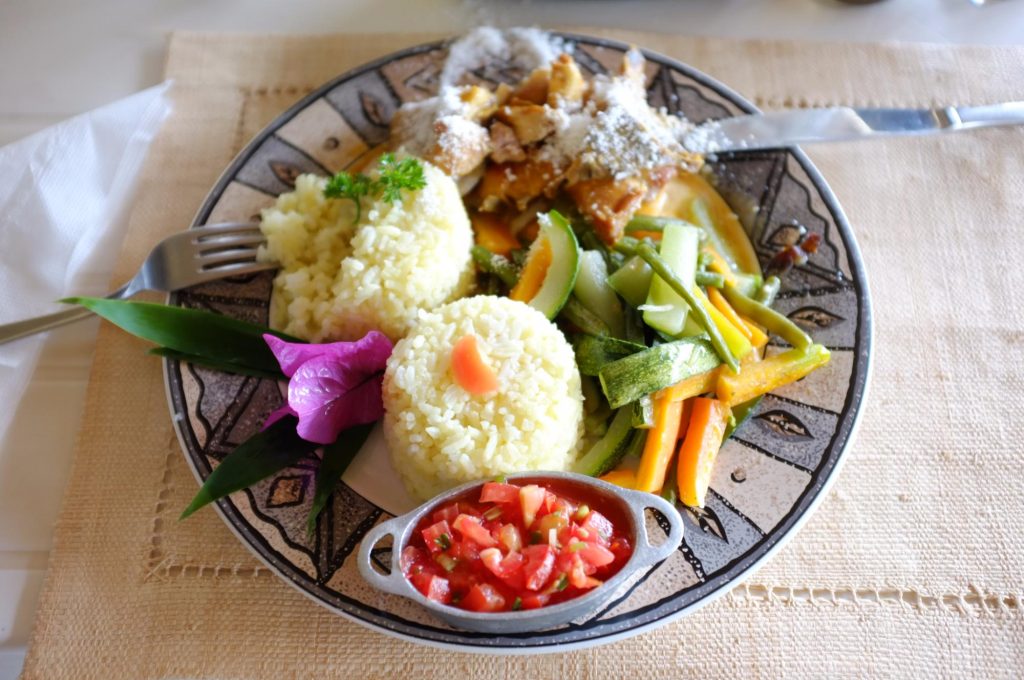 A Malagasy meal of rice, chicken and vegetables served with a bowl of fresh tomato relish